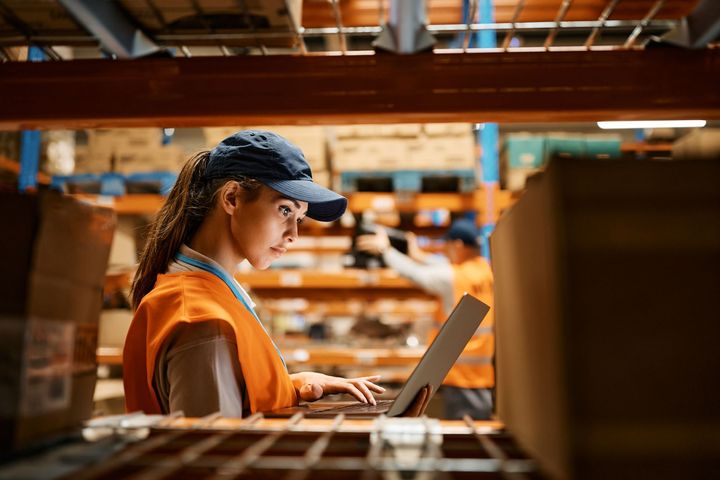 A young woman uses inventory management system to look for inventory in a warehouse.